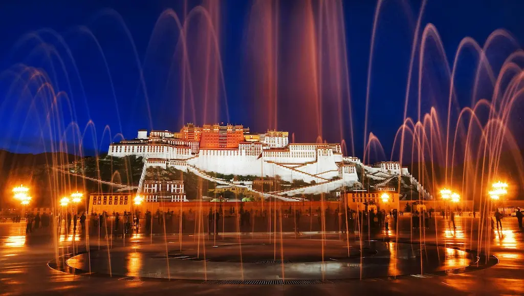Tibetdaily banner featuring the illuminated Potala Palace with long-exposure, orange-lit water fountains in the foreground at dusk.