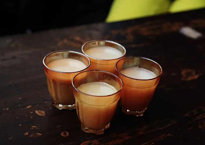 Four glasses of creamy Tibetan sweet tea sit on a dark wooden table at the Ani Tsangkung Nunnery tea house.