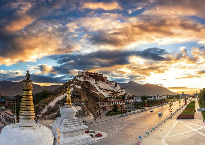 White stupas on Chagpori Hill frame Potala Palace and Potala Square under a golden sunrise sky