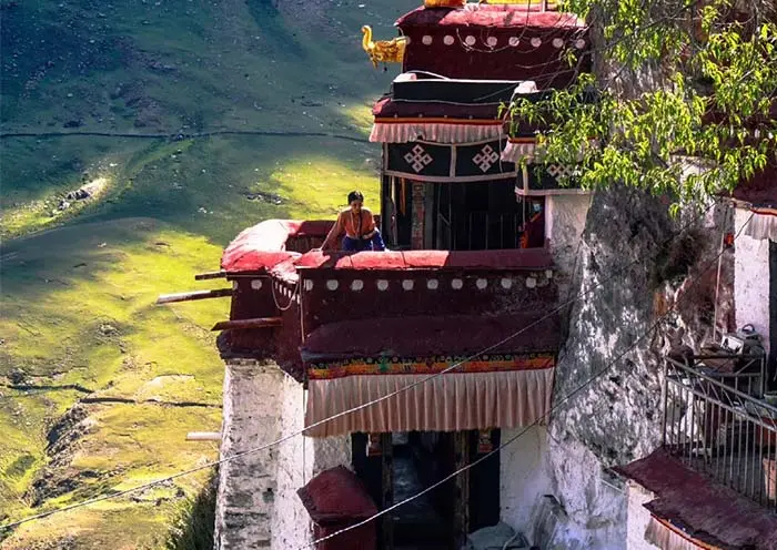 Drak Yerpa Monastery is famous for its cliff-hanging temples. This image perfectly depicts the serene interaction between visitors and the ancient religious structures overlooking the Tibetan valleys.