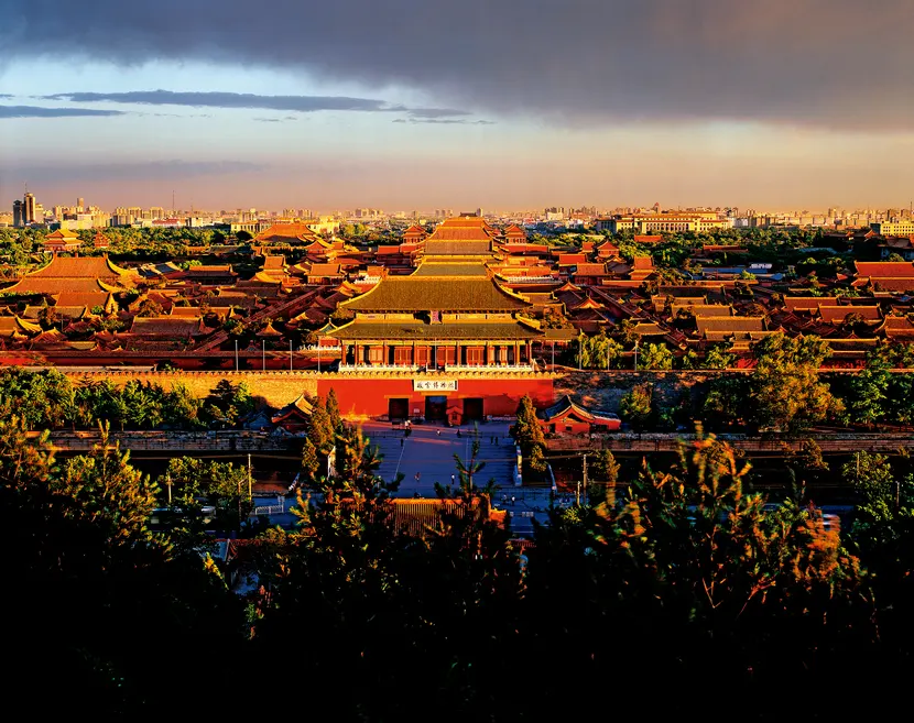 A breathtaking high-altitude aerial view of the entire Forbidden City palace complex in Beijing, showcasing the strict symmetrical layout of golden-roofed pavilions along the central axis.