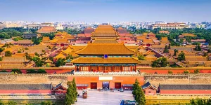 A wide shot of the grand Hall of Supreme Harmony in the Forbidden City, featuring its double-eaved golden roof, red lacquered doors, and massive stone courtyard in Beijing, China.