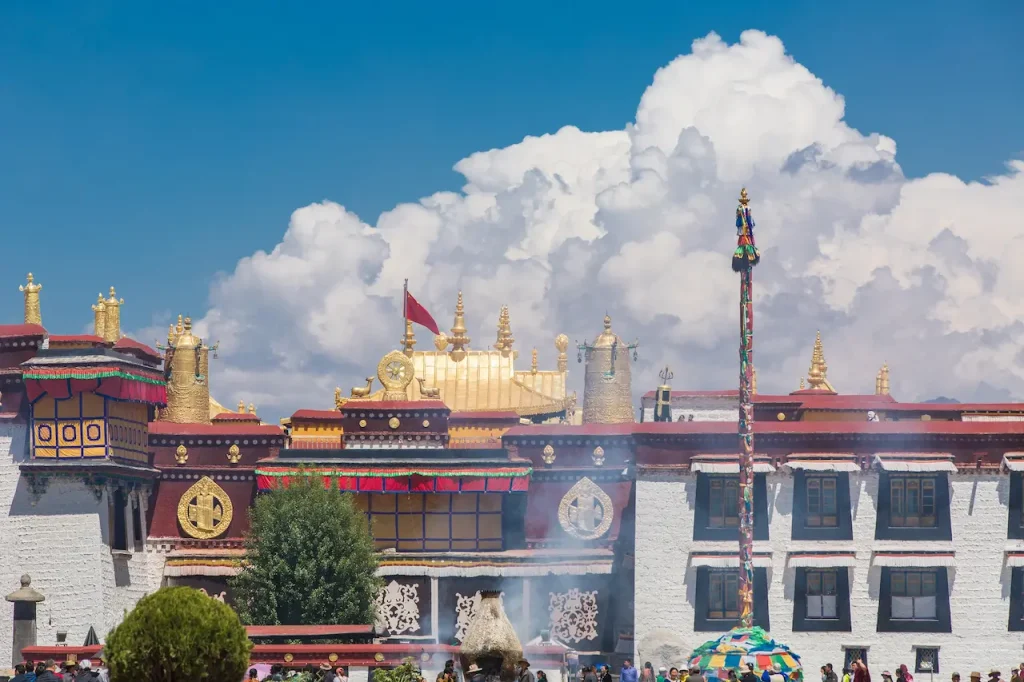Detailed view of traditional Tibetan carvings and colorful eaves at Jokhang Temple under a clear blue sky.