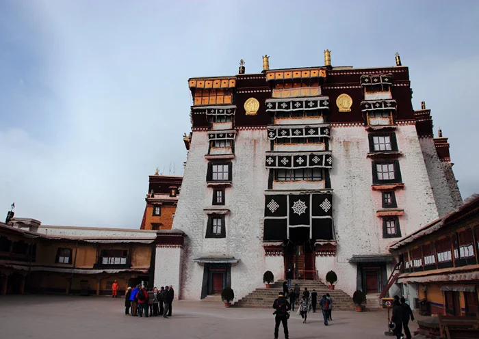 Tourists visiting the majestic inner courtyard and white facade of the Potala Palace in Lhasa.
