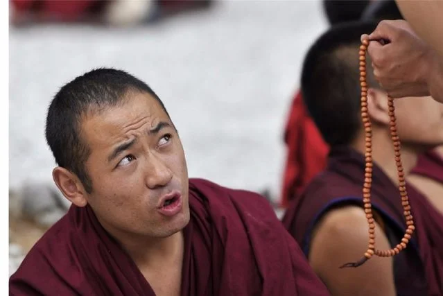 A close-up of a Tibetan monk during the traditional debate at Sera Monastery, capturing intense focus.