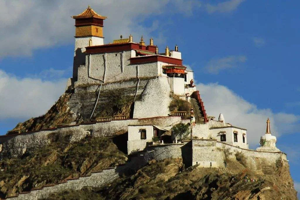 A close-up view of Yumbulagang palace, showing its white walls and golden roof against a blue sky in Shannan.